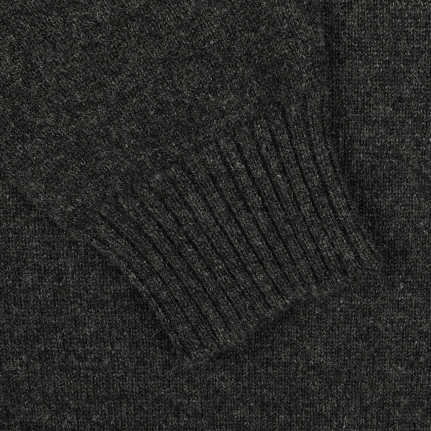 Close-up of a dark gray knit fabric, focusing on a ribbed sleeve cuff of the Charcoal Grey Crew Neck Lambswool Sweater by William Lockie—perfect for achieving a smart casual look.