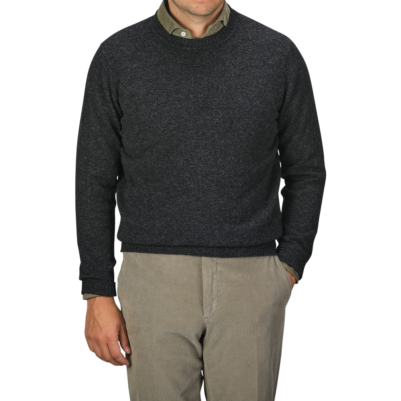 A man in a William Lockie Charcoal Grey Crew Neck Lambswool Sweater and beige pants stands against a plain background, with his left hand partially visible in his pocket. Only his torso is shown.