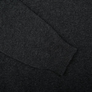 A close up of a William Lockie Charcoal Grey V-neck Lambswool Sweater on a black background, perfect for a business look.
