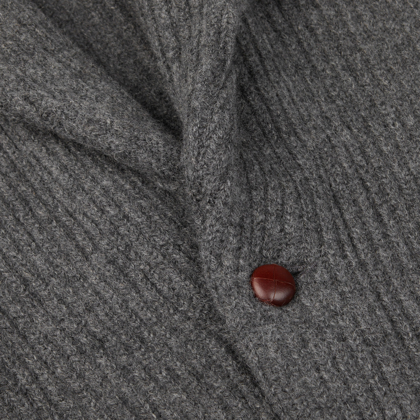 A close up of a William Lockie Cliff Grey Lambswool Shawl Collar Cardigan with leather buttons.