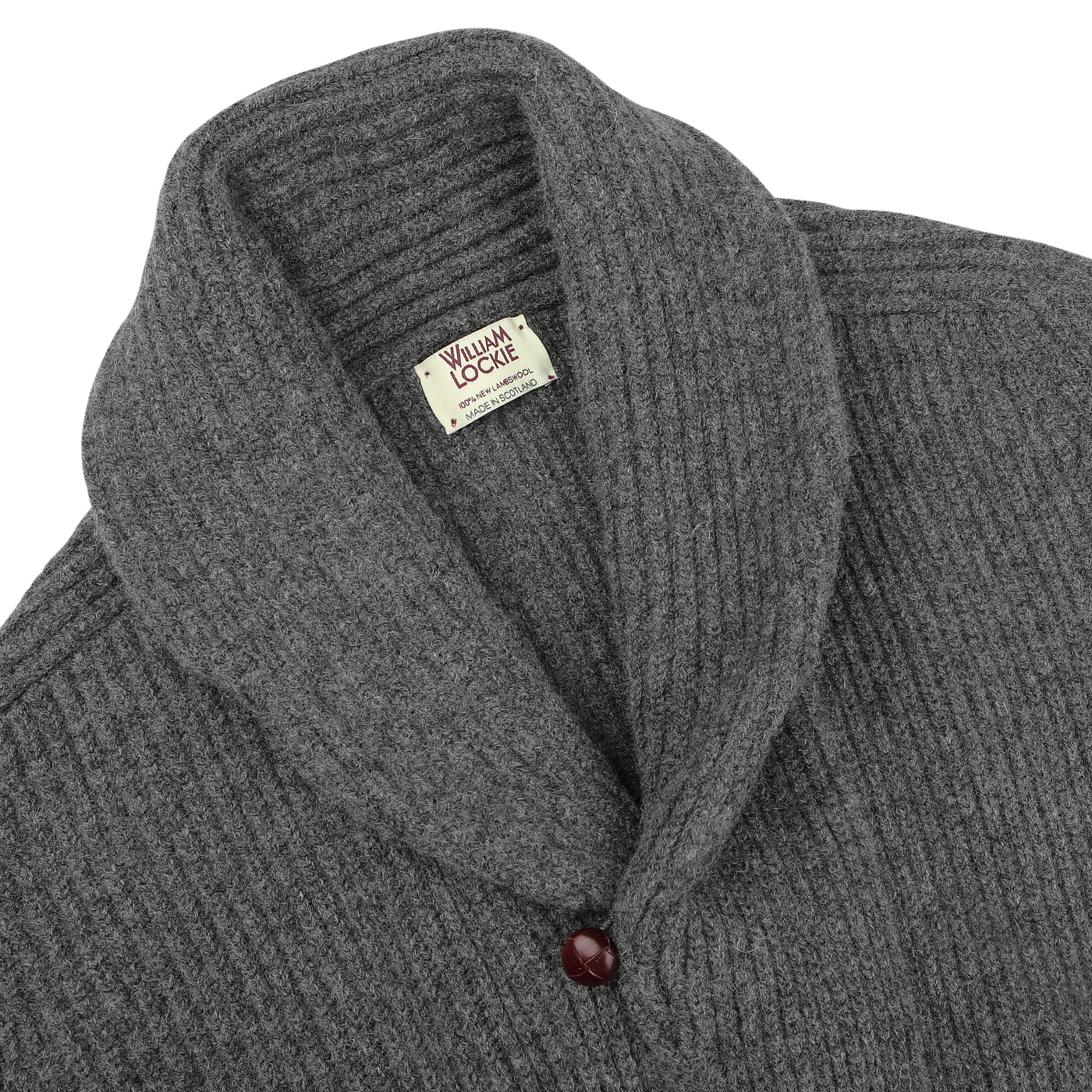 The Cliff Grey Lambswool Shawl Collar Cardigan from William Lockie is showcased. Made from soft Scottish lambswool, this gray, ribbed-knit cardigan features a single maroon button near the bottom of the collar.