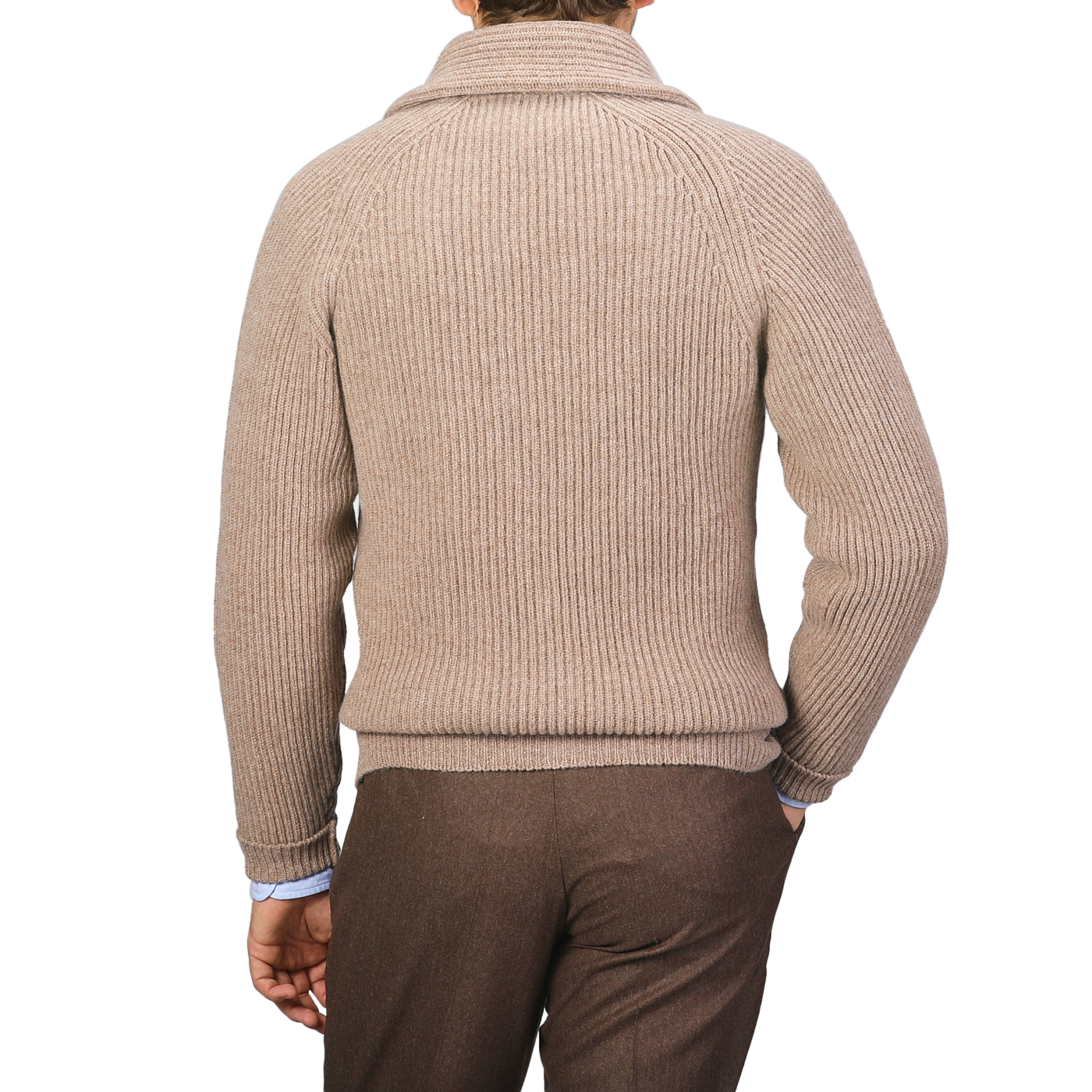 A person is seen from the back, dressed in a colt beige ribbed turtleneck sweater and soft brown pants. The attire exudes cozy elegance reminiscent of Scottish lambswool, distinctively styled without any leather buttons or a William Lockie Colt Beige Lambswool Shawl Collar Cardigan visible.