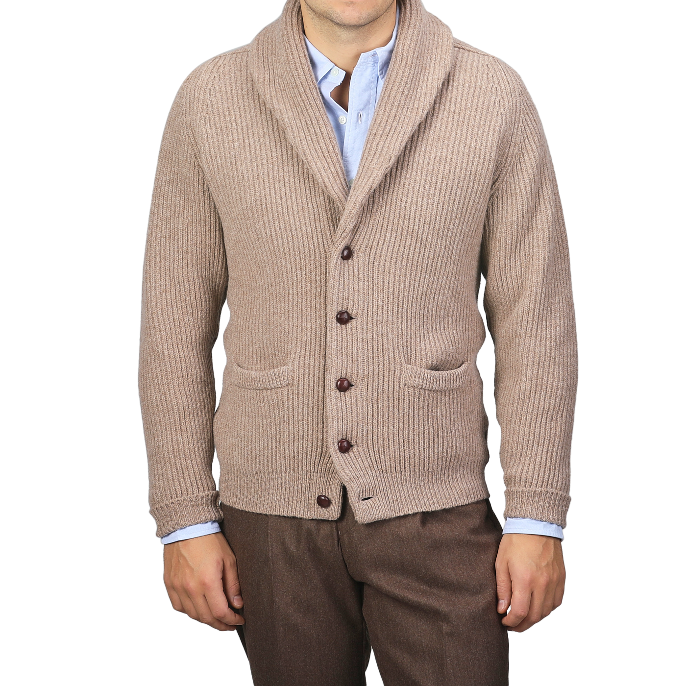 A person is dressed in a Colt Beige Lambswool Shawl Collar Cardigan by William Lockie over a light blue shirt and brown pants. The cardigan, adorned with leather buttons and two front pockets, adds a touch of timeless elegance.