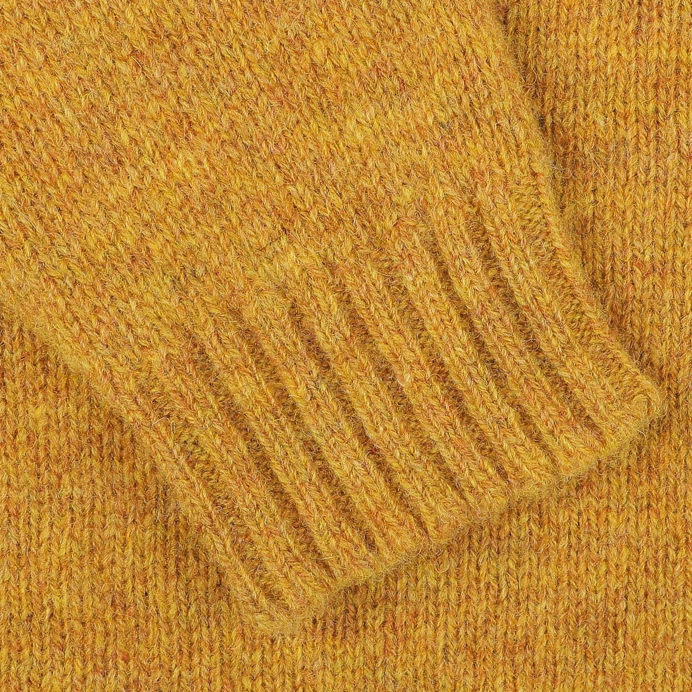 A close-up of the Cumin Brushed Shetland Lambswool Crew Neck sweater highlights the textured sleeve with ribbed cuff detailing. This luxurious knitwear underscores William Lockie's impeccable craftsmanship.