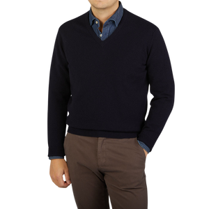A man wearing a comfy William Lockie Dark Navy V-Neck Lambswool sweater and brown pants.