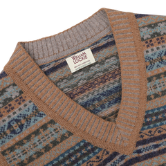 A close-up of the Driftwood Brown Fair Isle V-Neck Lambswool Slipover made from Scottish lambswool with a William Lockie label sewn on the inside of the collar. The slipover features a V-neck and a pattern of stripes and geometric shapes.