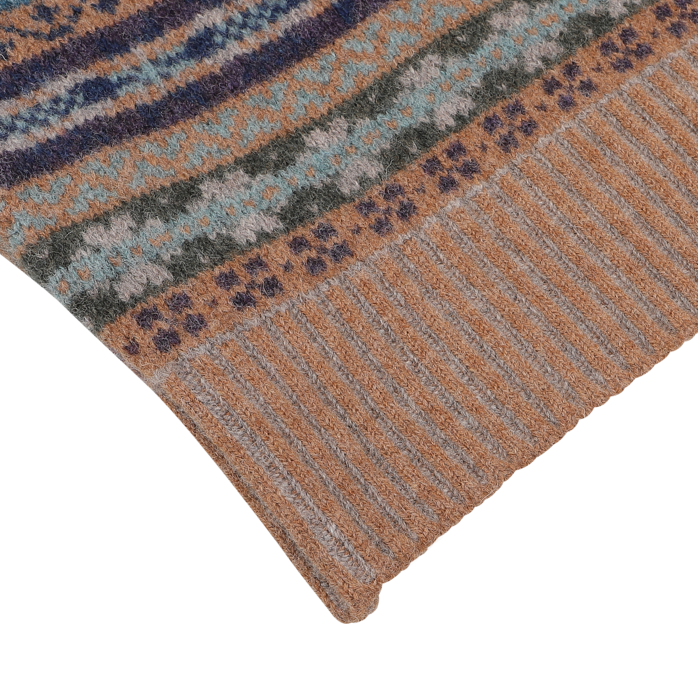 A close-up of a knitted fabric from William Lockie's Driftwood Brown Fair Isle V-Neck Lambswool Slipover, showcasing a mix of geometric patterns in various colors, including shades of driftwood brown, gray, blue, and green. The edge features the ribbed texture typical of William Lockie's Scottish lambswool garments.