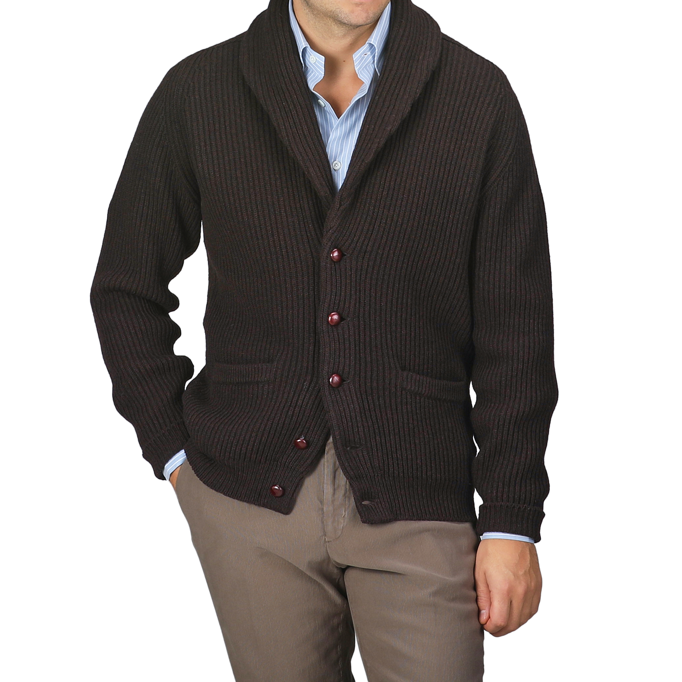 A person dressed in a William Lockie Ebony Brown Lambswool Shawl Collar Cardigan featuring leather buttons, styled over a light blue shirt and teamed with brown pants.