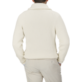 A person is seen from behind wearing the William Lockie Ecru Beige Lambswool Shawl Collar Cardigan and beige pants, standing against a plain gray background.