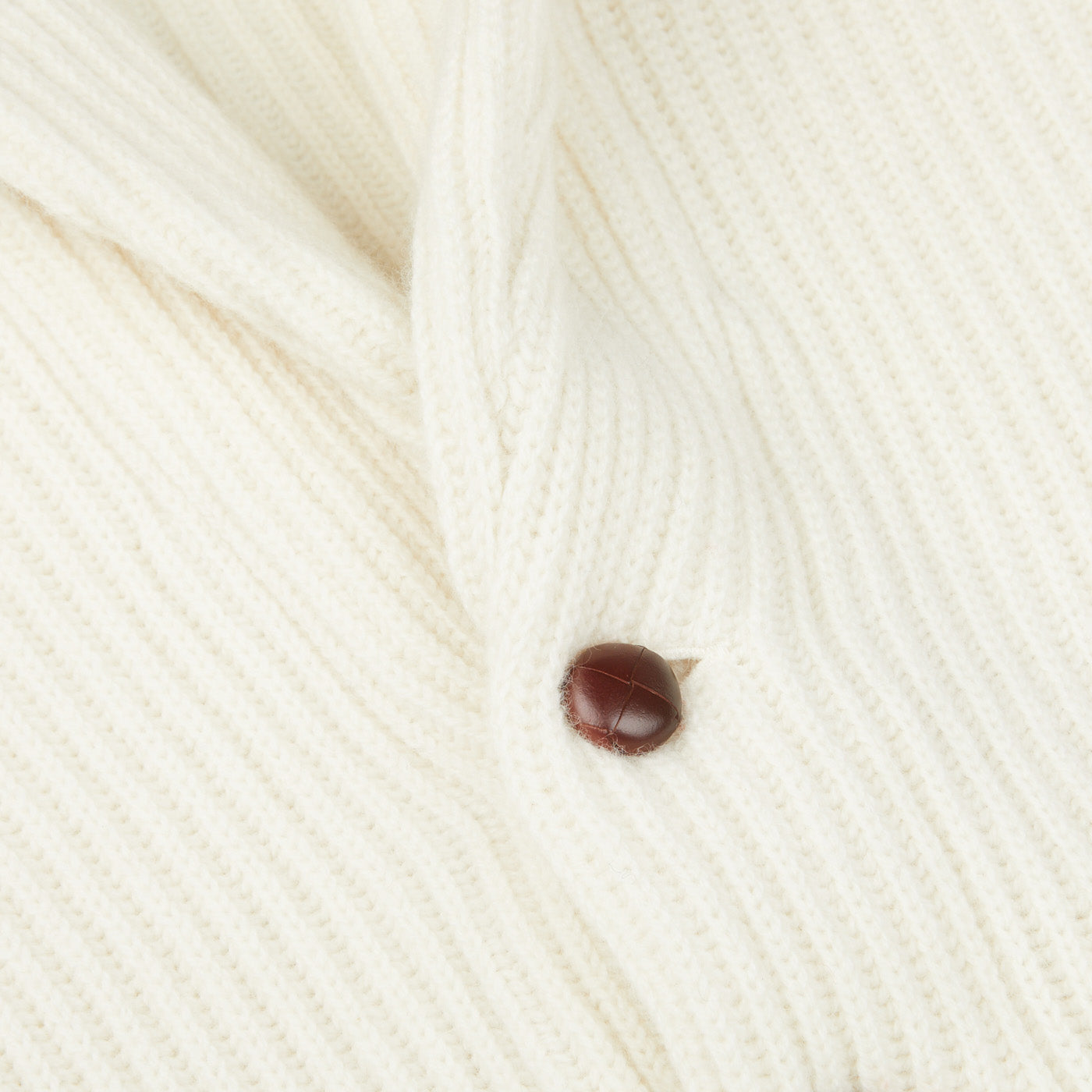 A close up of a Scottish William Lockie Ecru Beige Lambswool Shawl Collar Cardigan with a brown button.