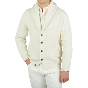 A man wearing a William Lockie Ecru Beige Lambswool Shawl Collar Cardigan and white pants.