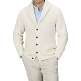 A person wearing a light blue shirt, beige pants, and an Ecru Beige Lambswool Shawl Collar Cardigan by William Lockie with leather buttons. The person's face is not visible.