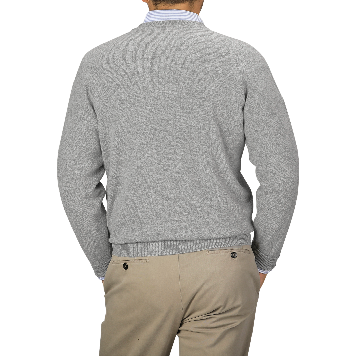 Image of a person seen from the back, wearing a William Lockie Flannel Grey Deep V-Neck Lambswool Sweater and beige pants. The person's left hand is in their pocket.