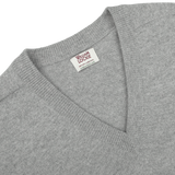 Close-up of a William Lockie Flannel Grey Deep V-Neck Lambswool Sweater, showcasing the visible brand label on the inside back collar.