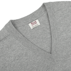 Close-up of a William Lockie Flannel Grey Deep V-Neck Lambswool Sweater, showcasing the visible brand label on the inside back collar.