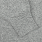 Close-up of the William Lockie Flannel Grey Deep V-Neck Lambswool Sweater, showcasing the textured knitted pattern and ribbed cuff of a sleeve.