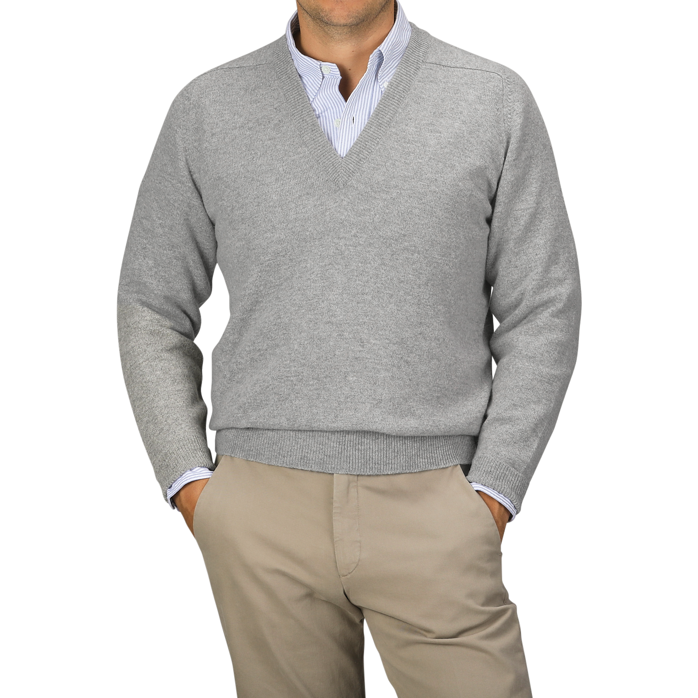 A person wearing a Flannel Grey Deep V-Neck Lambswool Sweater by William Lockie over a collared shirt and beige pants stands against a plain background.