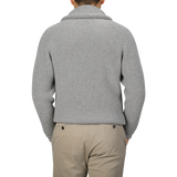 Rear view of a person wearing the Flannel Grey Lambswool Shawl Collar Cardigan by William Lockie, paired with beige pants.