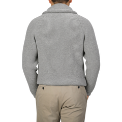 Rear view of a person wearing the Flannel Grey Lambswool Shawl Collar Cardigan by William Lockie, paired with beige pants.