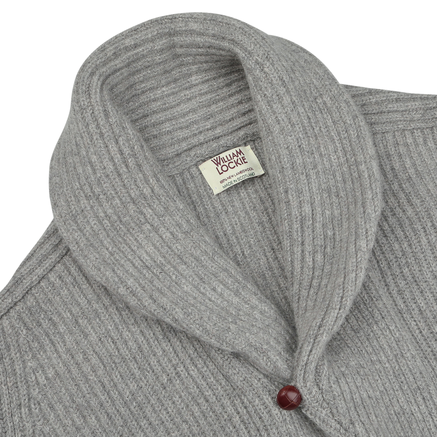 Close-up of the Flannel Grey Lambswool Shawl Collar Cardigan by William Lockie, showcasing its pure Scottish lambswool fabric, a tag labeled "William Lockie" at the neckline, and a single red leather button.