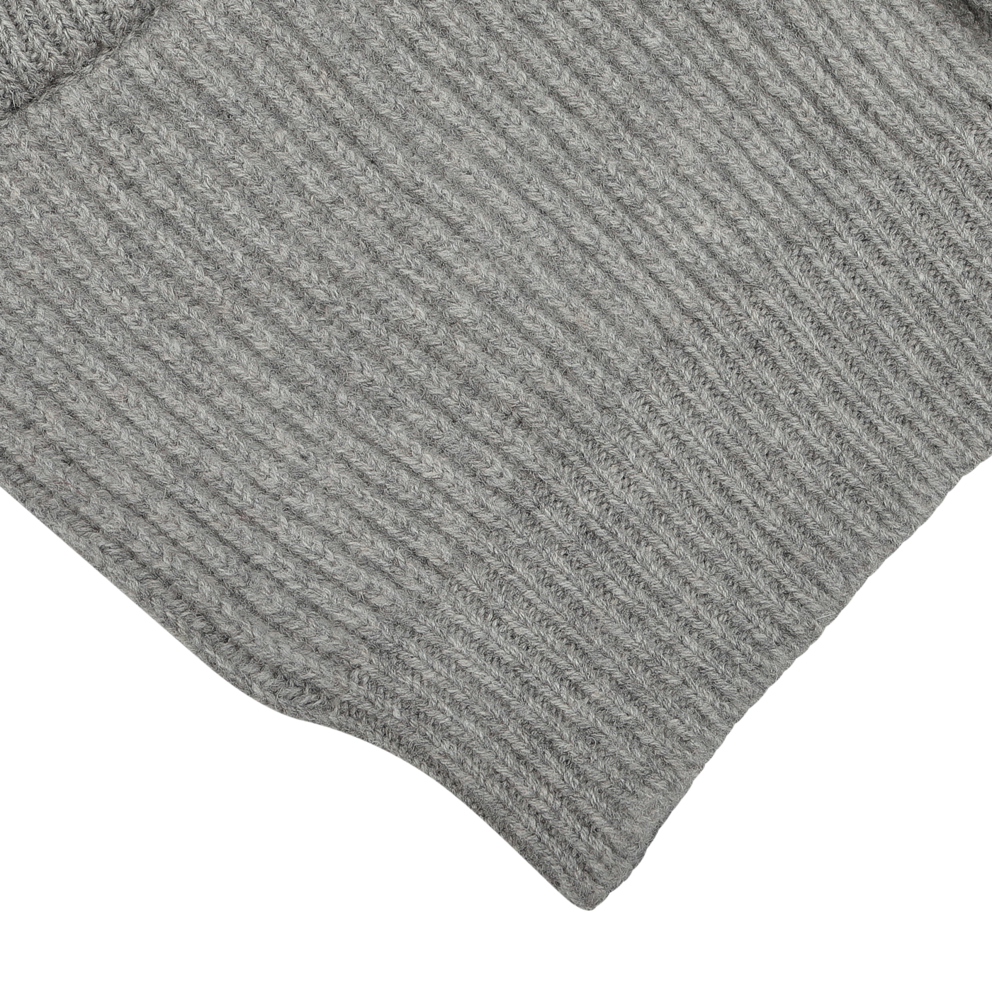 Close-up of a gray ribbed knit fabric, possibly part of the William Lockie Flannel Grey Lambswool Shawl Collar Cardigan with leather buttons.