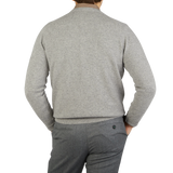 The back view of a man wearing a William Lockie Flannel Grey V-Neck Lambswool Sweater and pants.