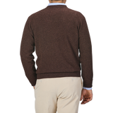 A person wearing a Hickory Brown Deep V-Neck Lambswool Sweater by William Lockie and beige pants is shown from the back in this image.