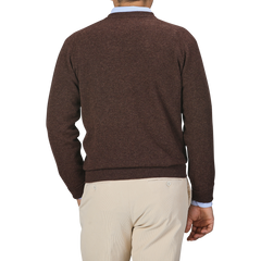 A person wearing a Hickory Brown Deep V-Neck Lambswool Sweater by William Lockie and beige pants is shown from the back in this image.