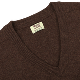 A close-up of the Hickory Brown Deep V-Neck Lambswool Sweater with a label inside the collar that reads "William Lockie, Made in Scotland.