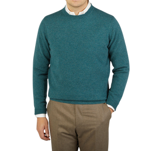 A man wearing a William Lockie Hunter Green Crew Neck Lambswool Sweater and tan pants.