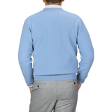 A person wearing a William Lockie Iceberg Blue Deep V-Neck Lambswool Sweater and gray pants is facing away from the camera against a plain background.