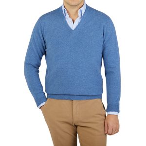 A man wearing a William Lockie Jeans Blue Lambswool V-Neck Sweater and khaki pants.