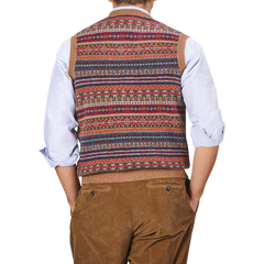 A person wearing a William Lockie Light Brown Fair Isle V-Neck Lambswool Slipover, a white shirt, and brown corduroy pants, viewed from the back.