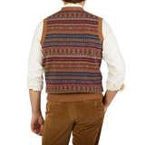 A man wearing a William Lockie Light Brown Fair Isle V-Neck Lambswool Slipover with a multi colored Scottish lambswool pattern.