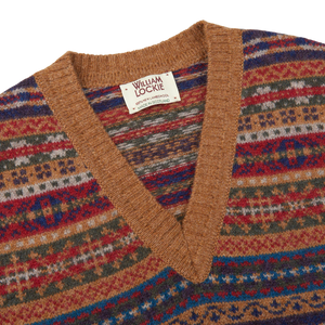 A multi-colored William Lockie V-neck sweater with a ribbed hem and light brown Fair Isle pattern, made from Scottish lambswool.