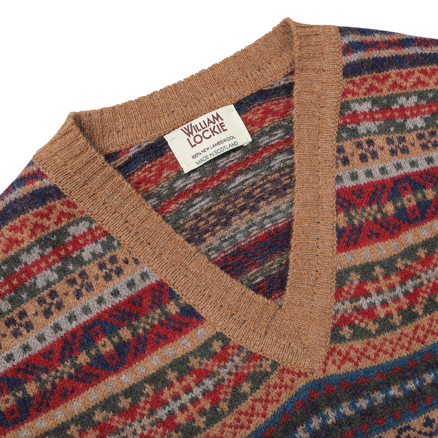 Close-up of a multicolored knit slipover with a geometric pattern, featuring a light brown V-neck collar and a label reading "William Lockie Made in Scotland," made from luxurious Scottish lambswool.