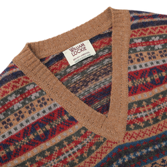 Close-up of a multicolored knit slipover with a geometric pattern, featuring a light brown V-neck collar and a label reading "William Lockie Made in Scotland," made from luxurious Scottish lambswool.