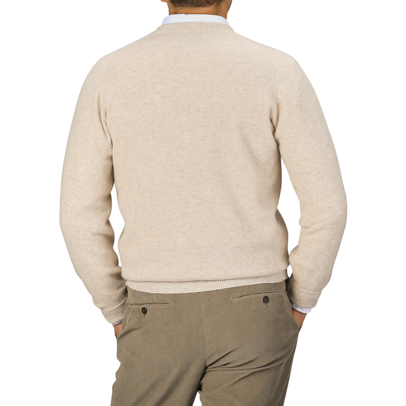 A person is shown from the back, wearing a Linen Beige Deep V-Neck Lambswool Sweater by William Lockie and light brown pants. Their hands are in their pockets.