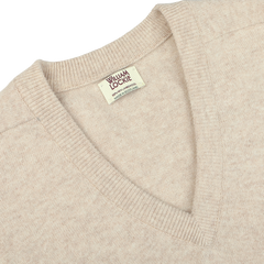 Close-up image of a Linen Beige Deep V-Neck Lambswool Sweater with a label that reads "William Lockie".