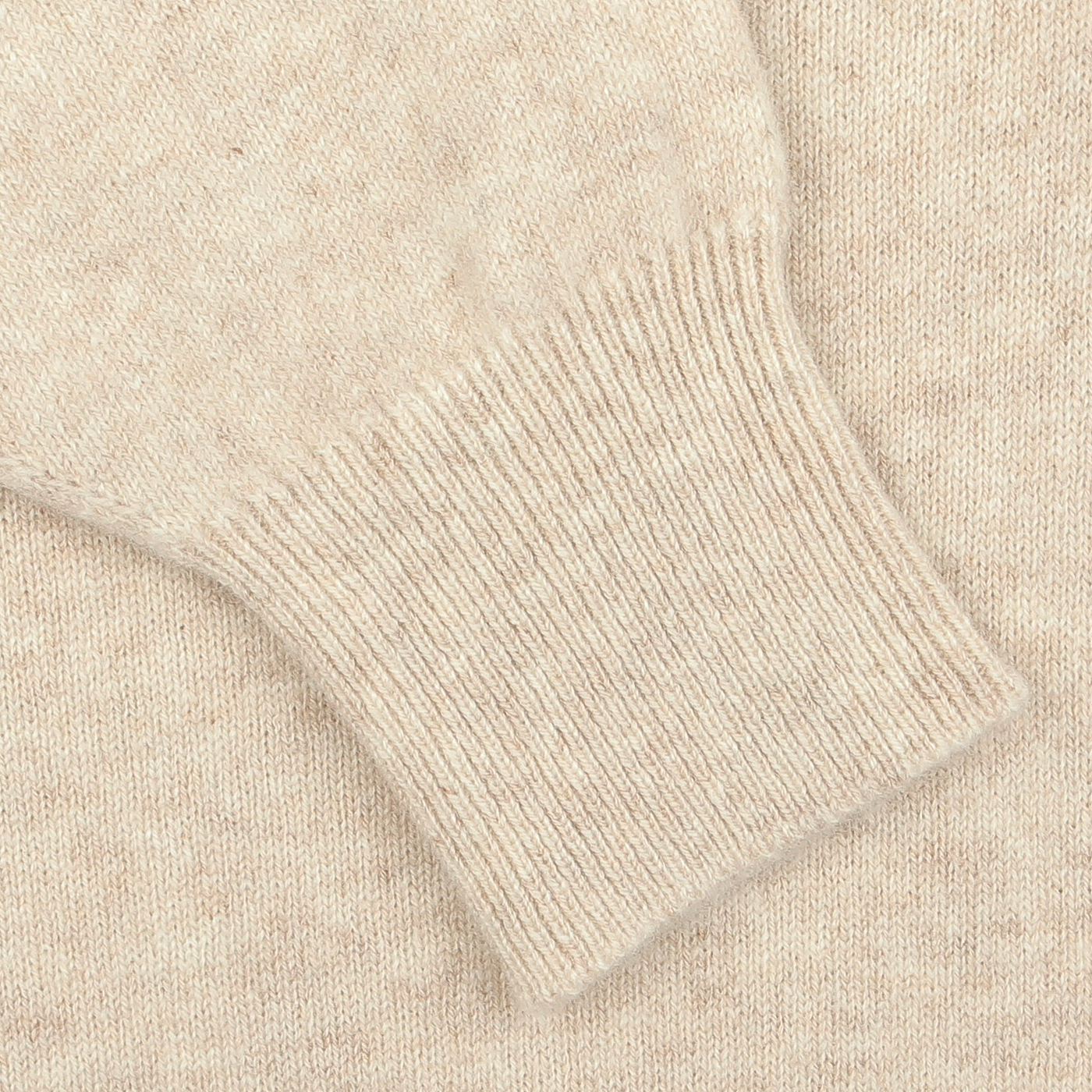 Close-up of a William Lockie Linen Beige Deep V-Neck Lambswool Sweater, showcasing the ribbed cuff detail on its sleeve.