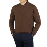 A man wearing a William Lockie Mocha Brown Crew Neck Lambswool Sweater and blue pants.