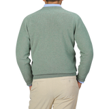 A person is shown from the back, wearing a William Lockie Mojito Green Deep V-Neck Lambswool Sweater and beige trousers.