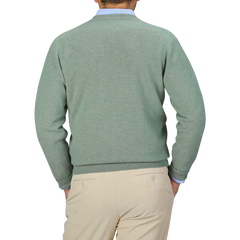 A person is shown from the back, wearing a William Lockie Mojito Green Deep V-Neck Lambswool Sweater and beige trousers.