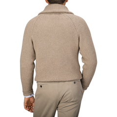 A person is seen from the back wearing a William Lockie Natural Beige Cashmere Shawl Collar Cardigan with leather buttons and light-colored pants.