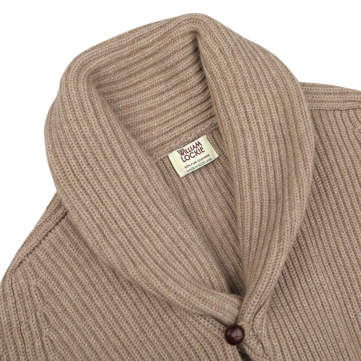 A natural beige cashmere shawl collar cardigan, accentuated by leather buttons, and a "William Lockie" brand label visible inside.