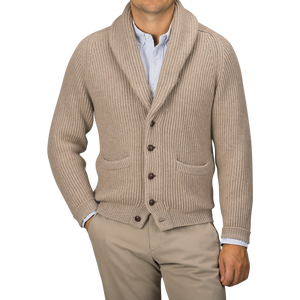 A person wearing a Natural Beige Cashmere Shawl Collar Cardigan by William Lockie with leather buttons over a light blue button-up shirt and khaki pants, hands in pockets.