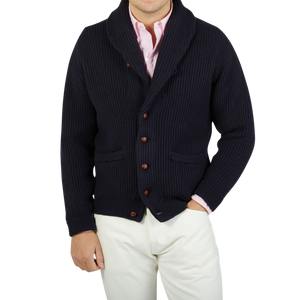 A man wearing a William Lockie Navy Blue Cashmere Shawl Collar Cardigan and white pants.