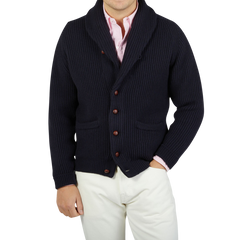 A man wearing a William Lockie Navy Blue Cashmere Shawl Collar Cardigan and white pants.