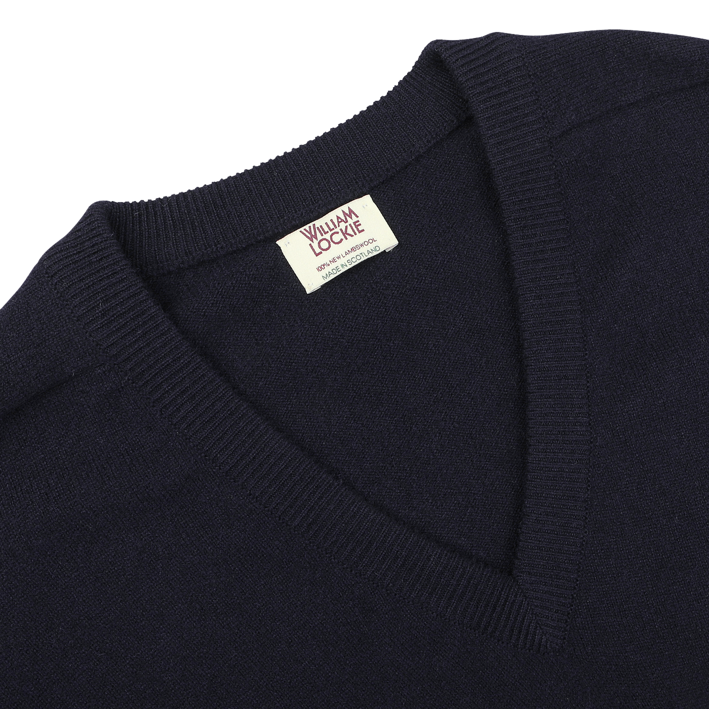 Close-up of a navy blue William Lockie sweater with a deep V-neck, revealing a tag on the collar.