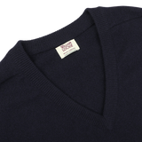 Close-up of a navy blue William Lockie sweater with a deep V-neck, revealing a tag on the collar.